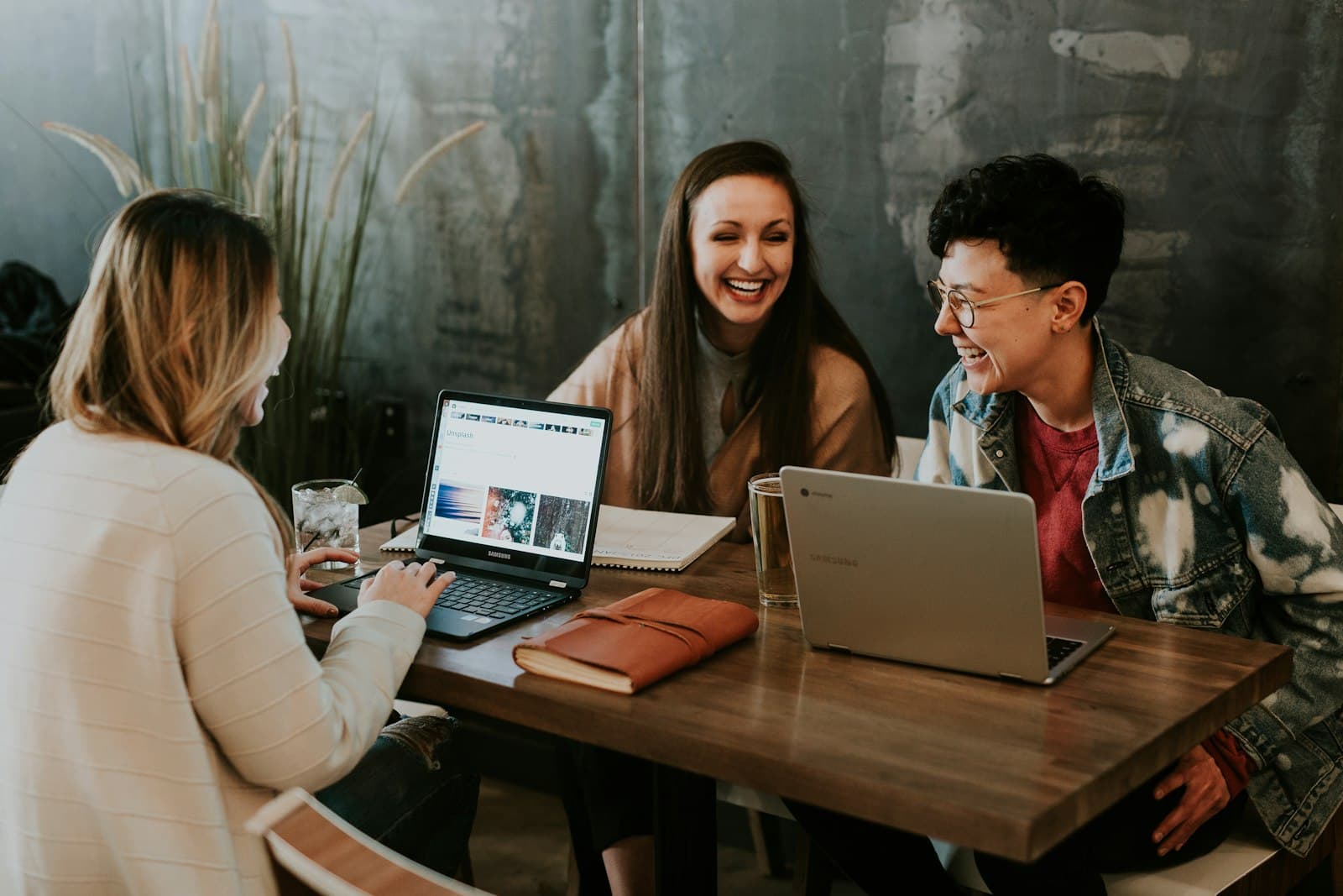 Three colleagues laughing together while working at a table